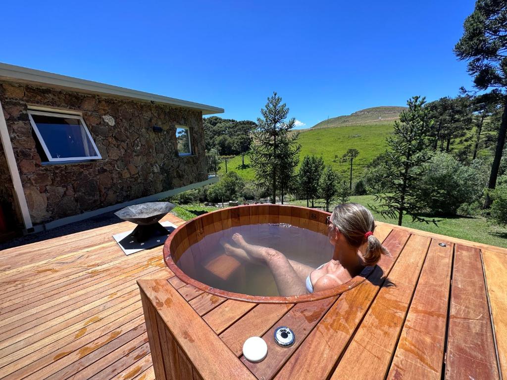 a woman in a hot tub on a deck at Refúgio Casa de Pedra in Cambara do Sul