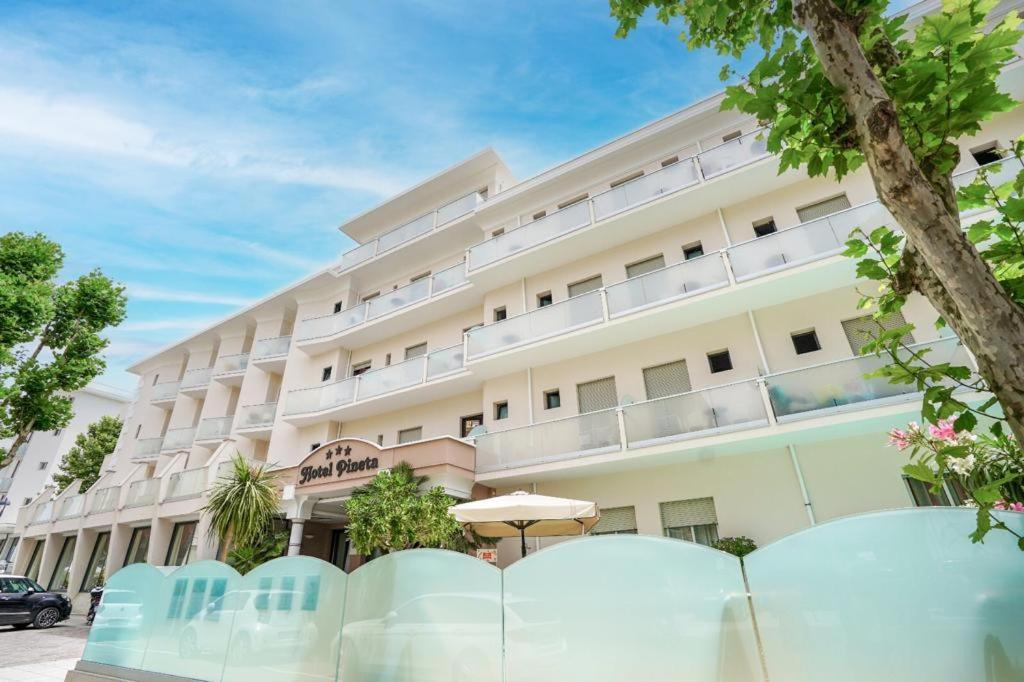 a hotel building with blue chairs in front of it at Hotel Pineta in Bellaria-Igea Marina