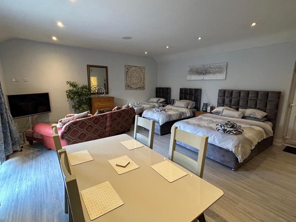 a room with two beds and a table and a couch at Southernwood - Family Studio in Didcot