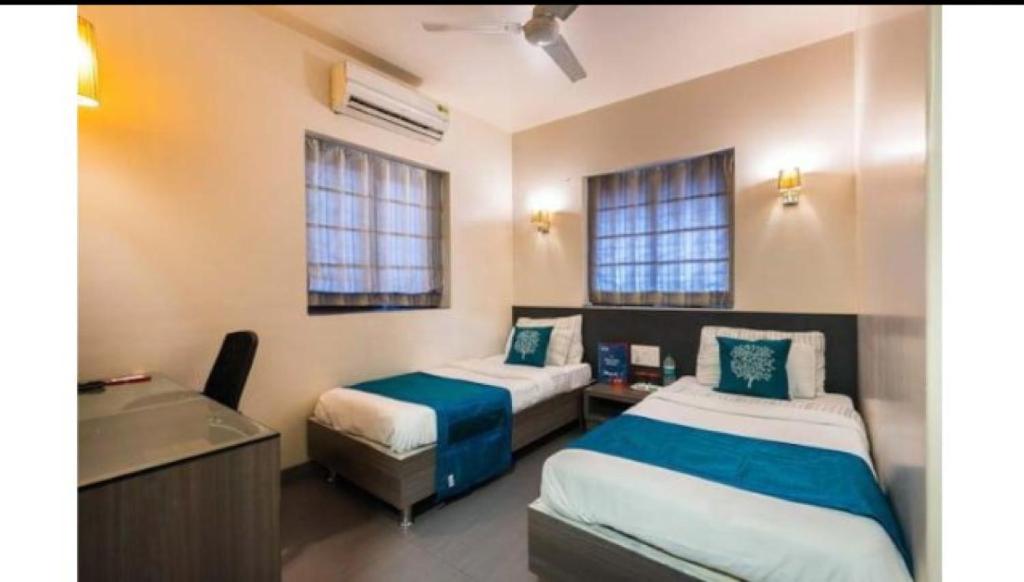 a bedroom with two beds and a desk and a sink at Apollo Guest House in Mumbai