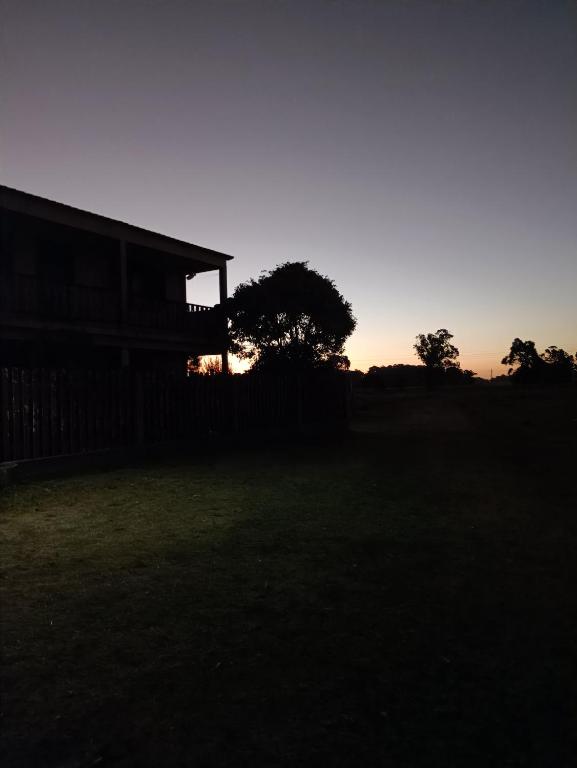 una casa en un campo con la puesta de sol en el fondo en Casa de campo, en Chuy