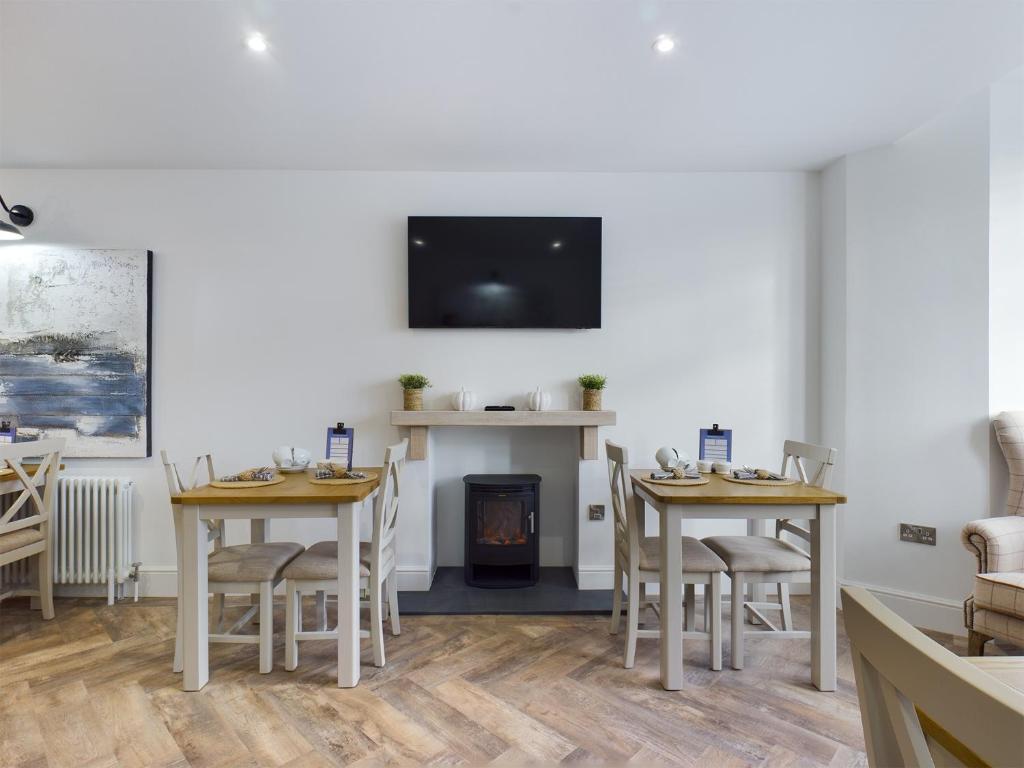 a dining room with two tables and a fire place at Driftwood Boutique Guest House in Rhosneigr