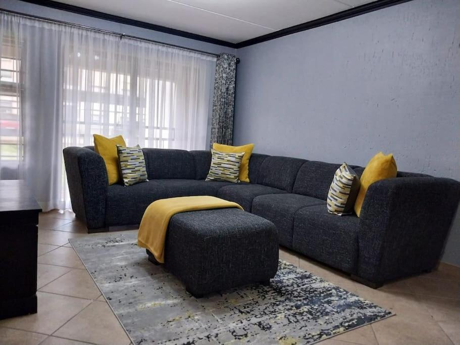 a living room with a blue couch and yellow pillows at Maneli 69 in Boksburg