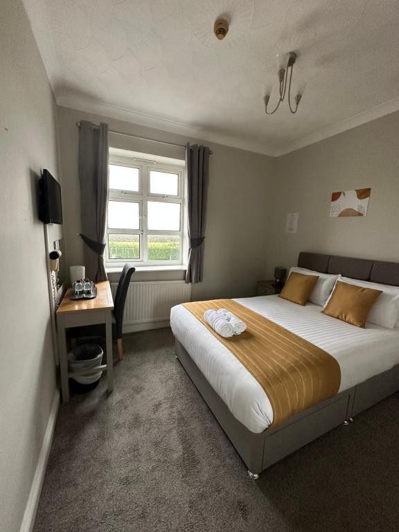 1 dormitorio con cama, escritorio y ventana en Rettendon Lodge en Battlesbridge