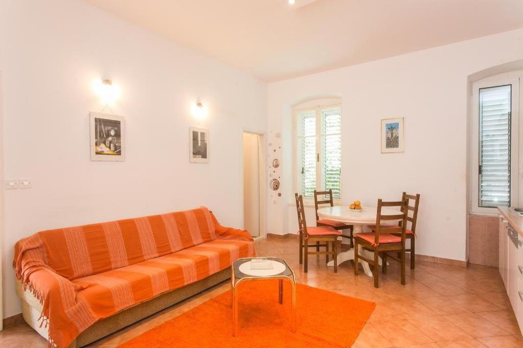 sala de estar con sofá naranja y mesa en Apartment Tranquilo, en Dubrovnik