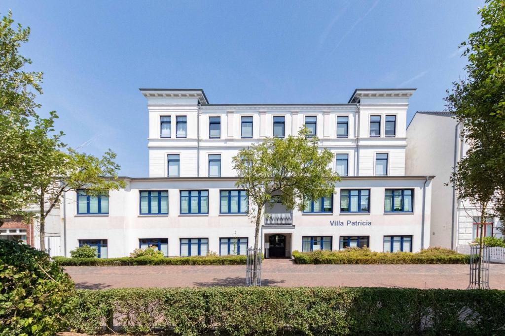ein großes weißes Gebäude mit Bäumen davor in der Unterkunft Apartment Wilhelmine in Borkum