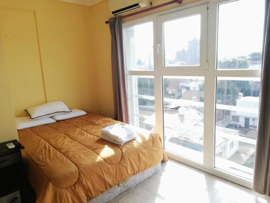 ein Schlafzimmer mit einem Bett und einem großen Fenster in der Unterkunft Apartamentos Itati in General Sarmiento