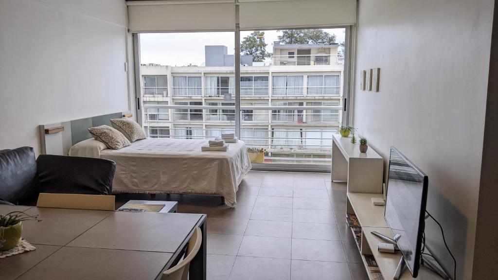 a living room with a bed and a large window at CONCORD PILAR"313 Almendros"50m2 en Suite -living y dormitorio- de 1 a 4 huéspedes in Pilar