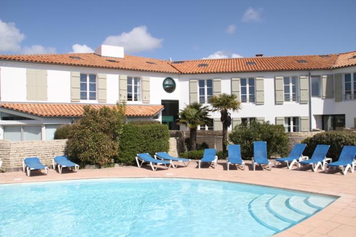 a swimming pool with blue chairs and a building at Appartement en duplex avec balcon, 5 minutes plage et centre village in La Couarde-sur-Mer