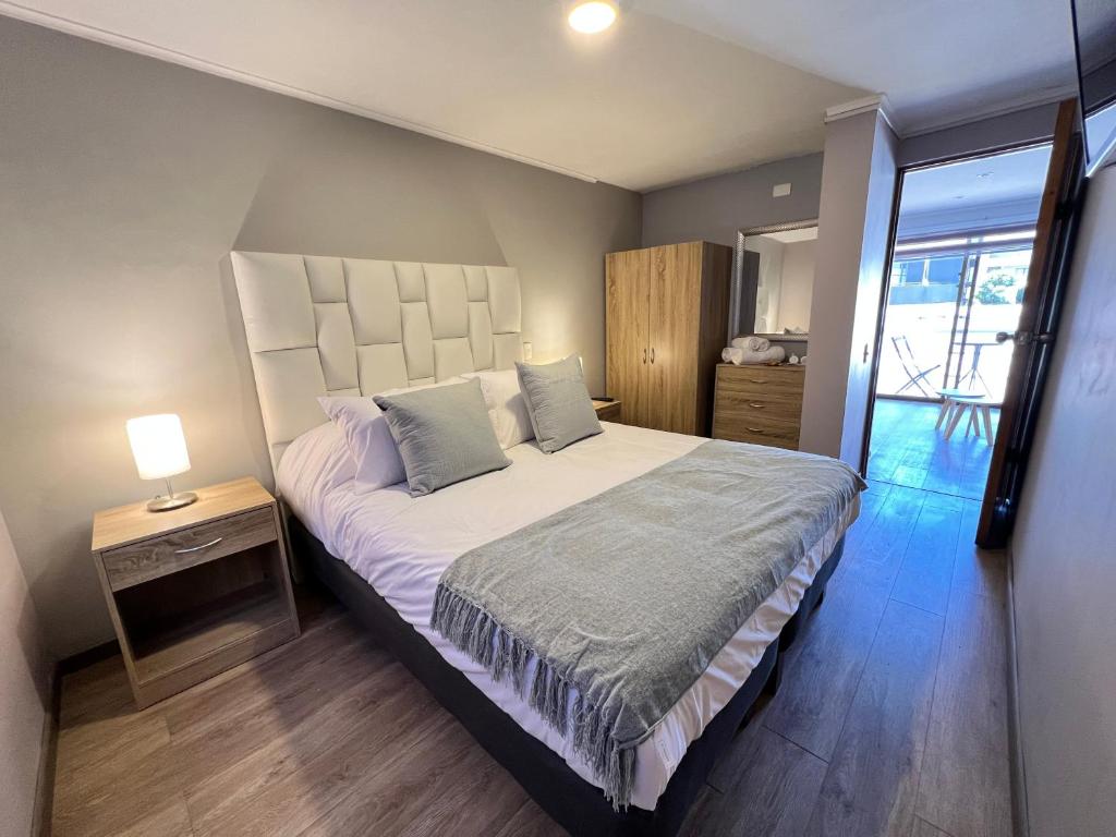 Un dormitorio con una cama grande y una mesa con una lámpara. en Spazios Apart Hotel Reñaca, en Viña del Mar