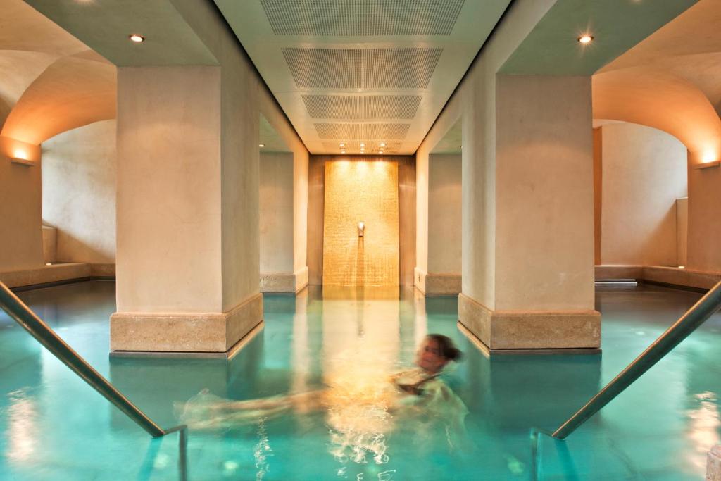 eine Person, die in einem Pool in einem Gebäude schwimmt in der Unterkunft Limmathof Baden - Boutique Haus & Spa in Ennetbaden