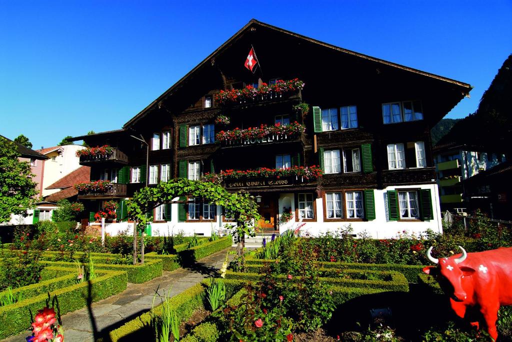 un bâtiment avec une vache devant lui dans l'établissement Hotel Chalet Swiss, à Interlaken