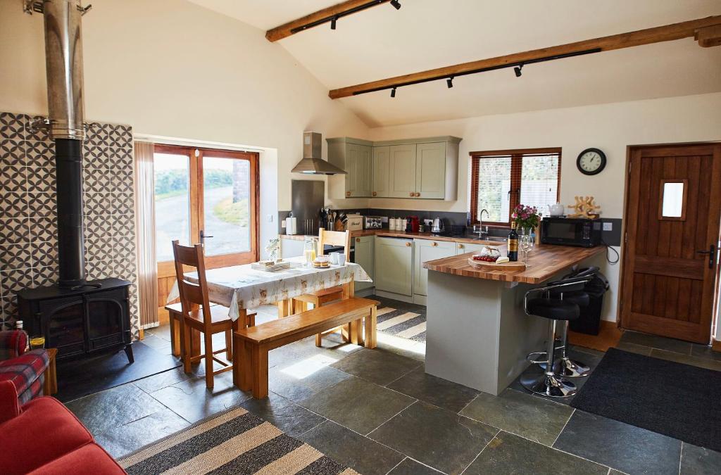 a kitchen with a table and a stove at The Old Dairy - Boutique Countryside Cottage at Harrys Cottages in Pen y Clawdd