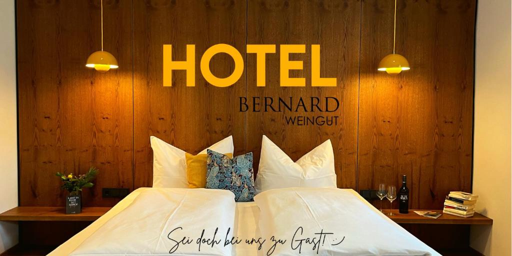 un dormitorio de hotel con una cama con sábanas y almohadas blancas en Hotel-Weingut Bernard en Sulzfeld am Main