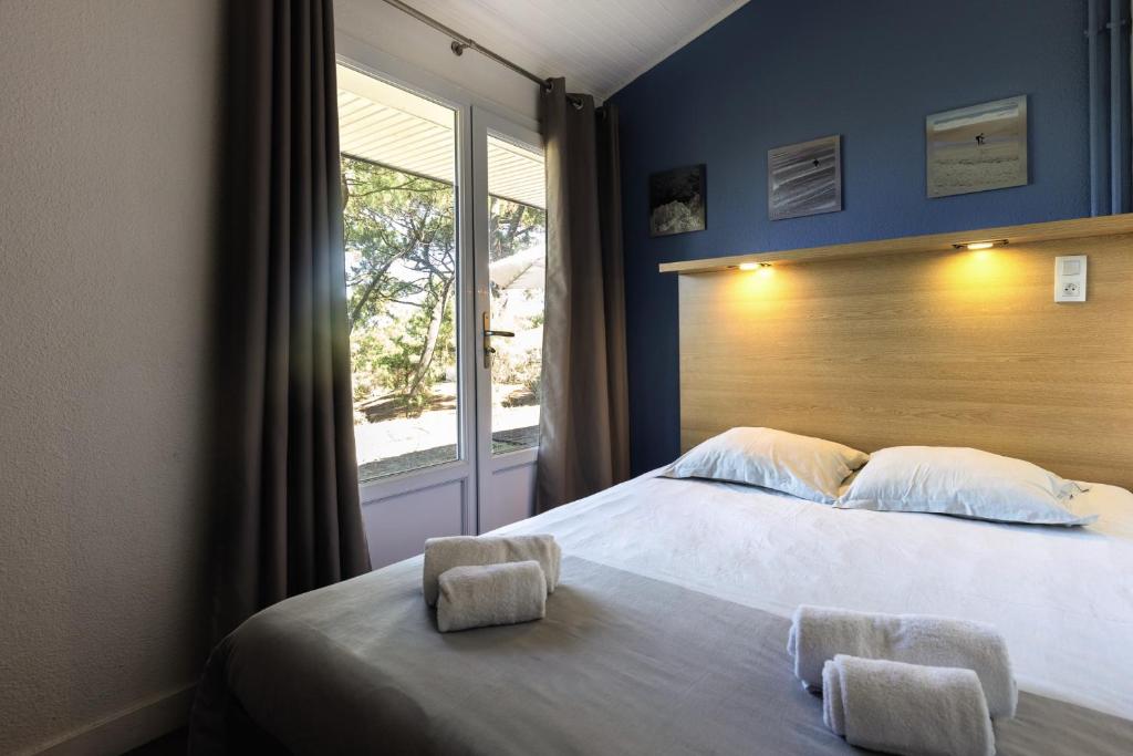 a bedroom with a large bed and a window at Belambra Clubs Capbreton - Les Vignes in Capbreton