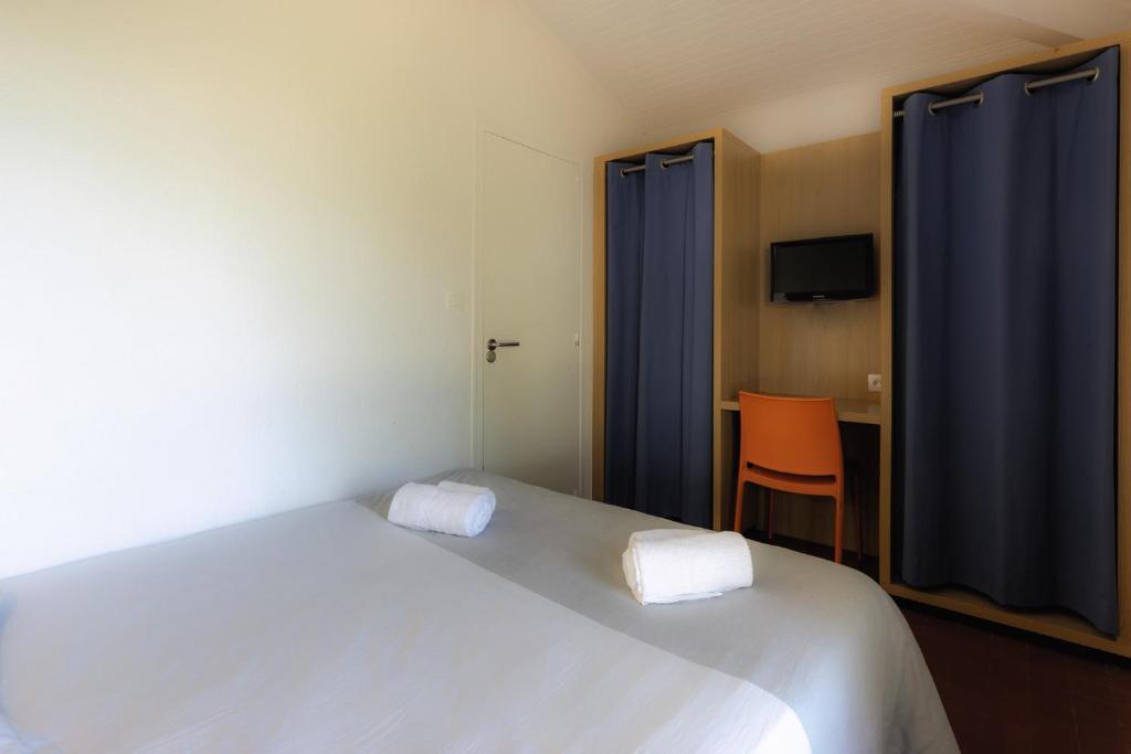 a bedroom with a large white bed and a chair at Belambra Clubs Capbreton - Les Vignes in Capbreton