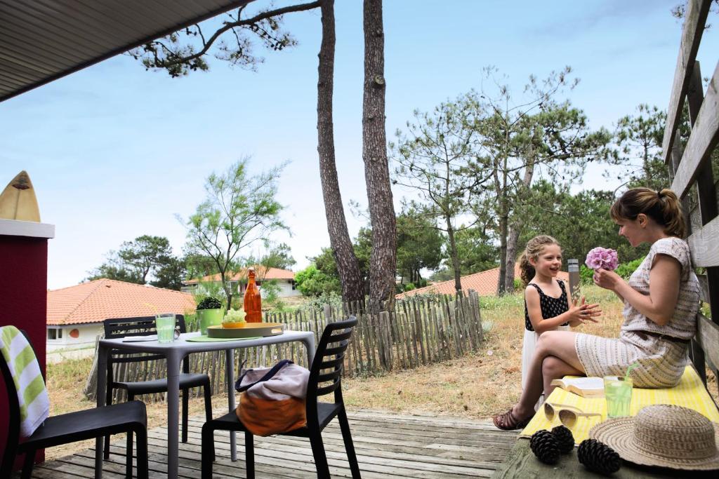 two girls sitting on a deck eating food at Belambra Clubs Capbreton - Les Vignes in Capbreton