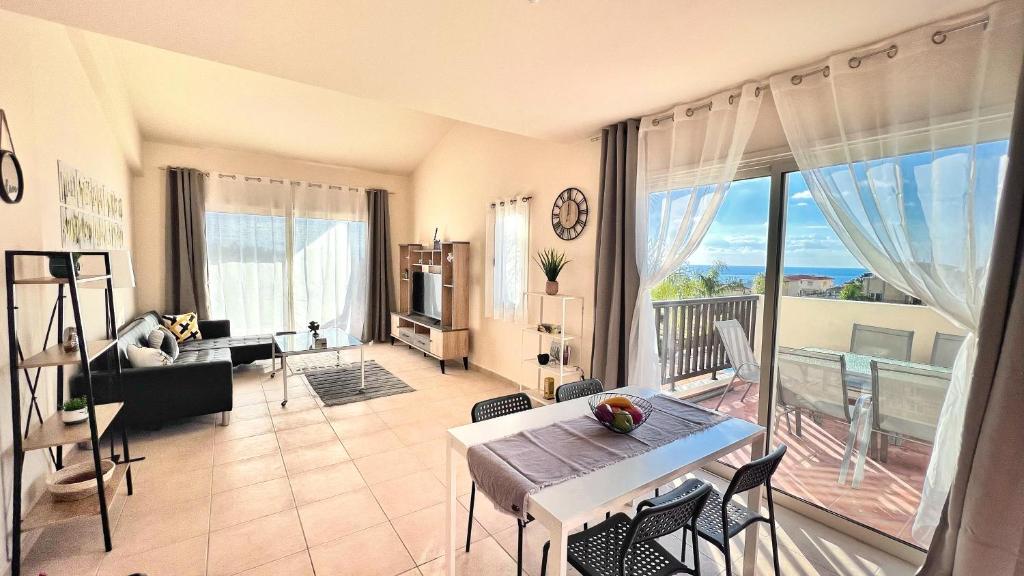 ein Wohnzimmer mit einem Tisch und Stühlen sowie einem großen Fenster in der Unterkunft Melanos Sea View Apartment in Paphos City