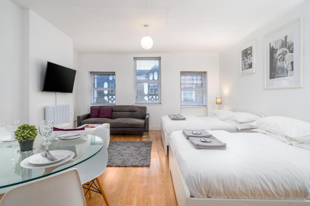 a white living room with a large bed and a table at Soho & Covent Garden Apartment, Sleeps 3 in London