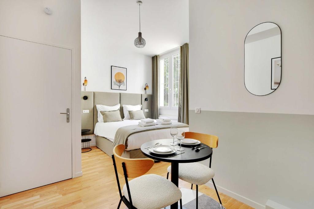 1 dormitorio con 1 cama, mesa y sillas en Résidence des Poissonniers, en París
