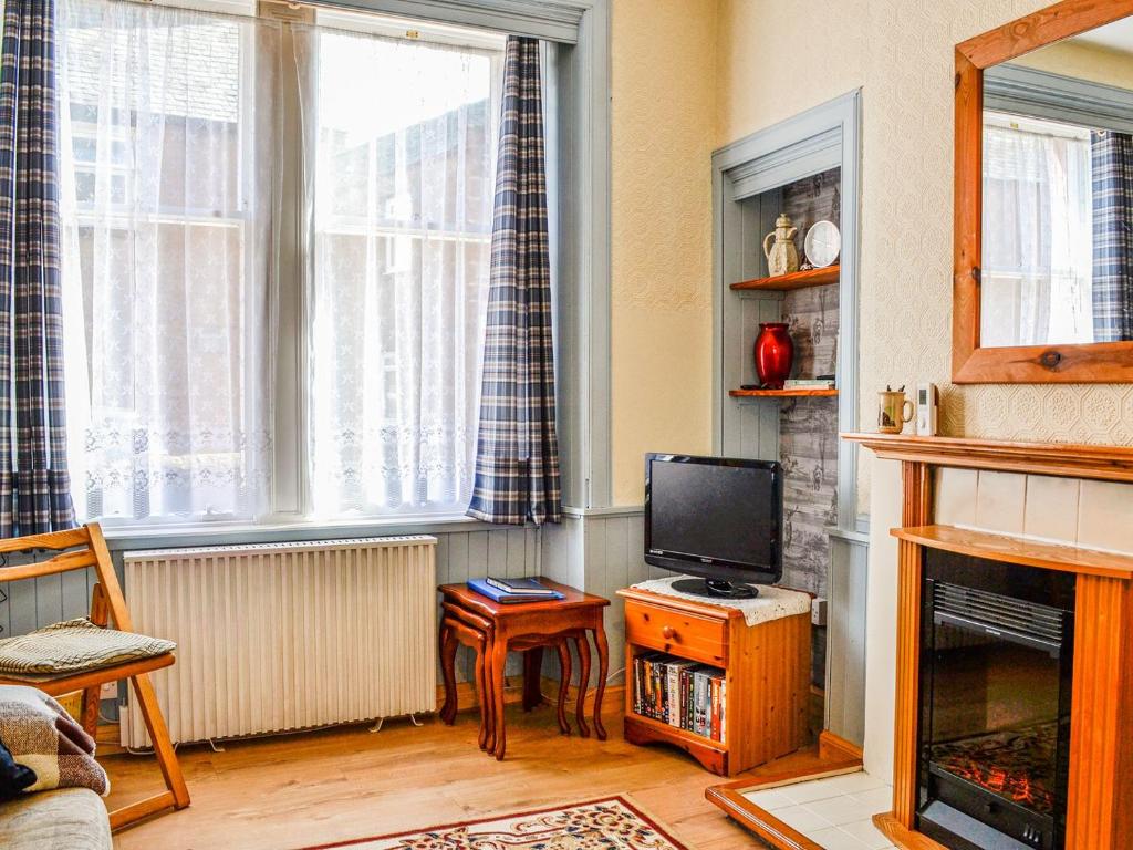 a living room with a television and a fireplace at Kirk Wynd Cottage in Kirriemuir