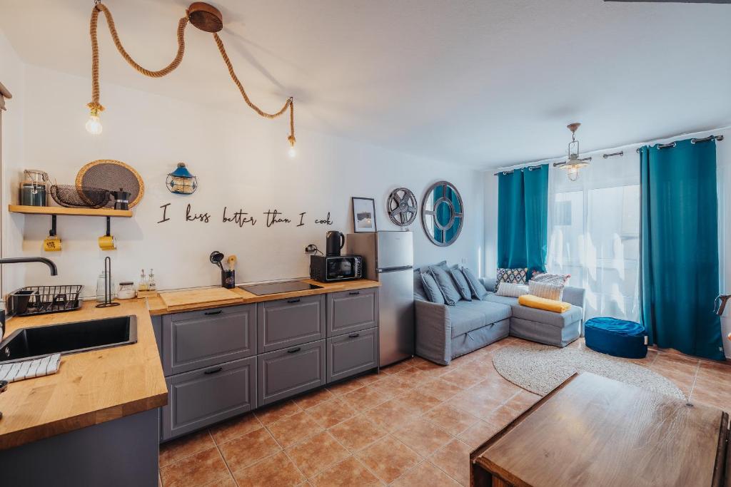 cocina y sala de estar con cortinas azules y sofá en Casa Allegranza, en Cotillo