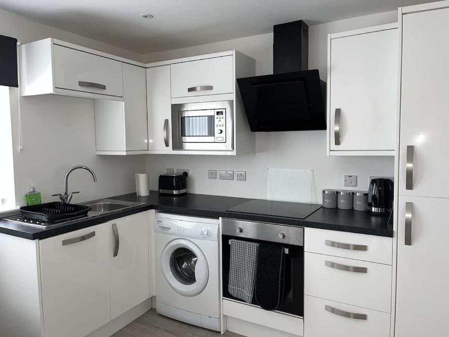 a kitchen with white cabinets and a washing machine at Lovely one bed, open plan studio apartment. in Culloden