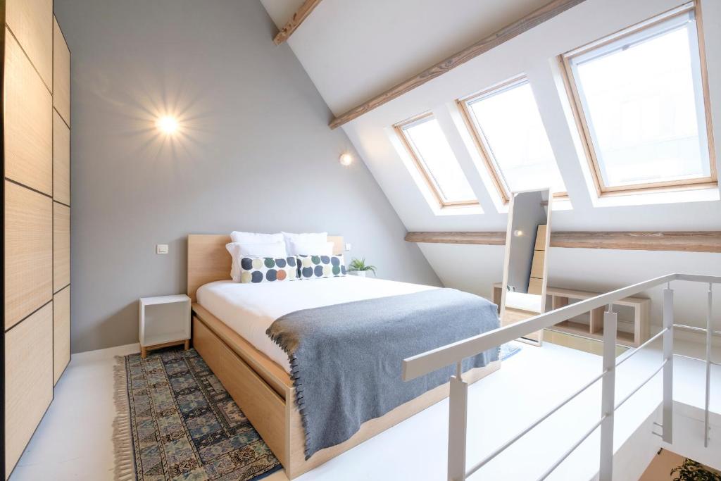 ブリュッセルにあるSplendide Duplex proche de la Grand-Placeの小さな屋根裏のベッドルーム(ベッド1台、窓2つ付)が備わります。