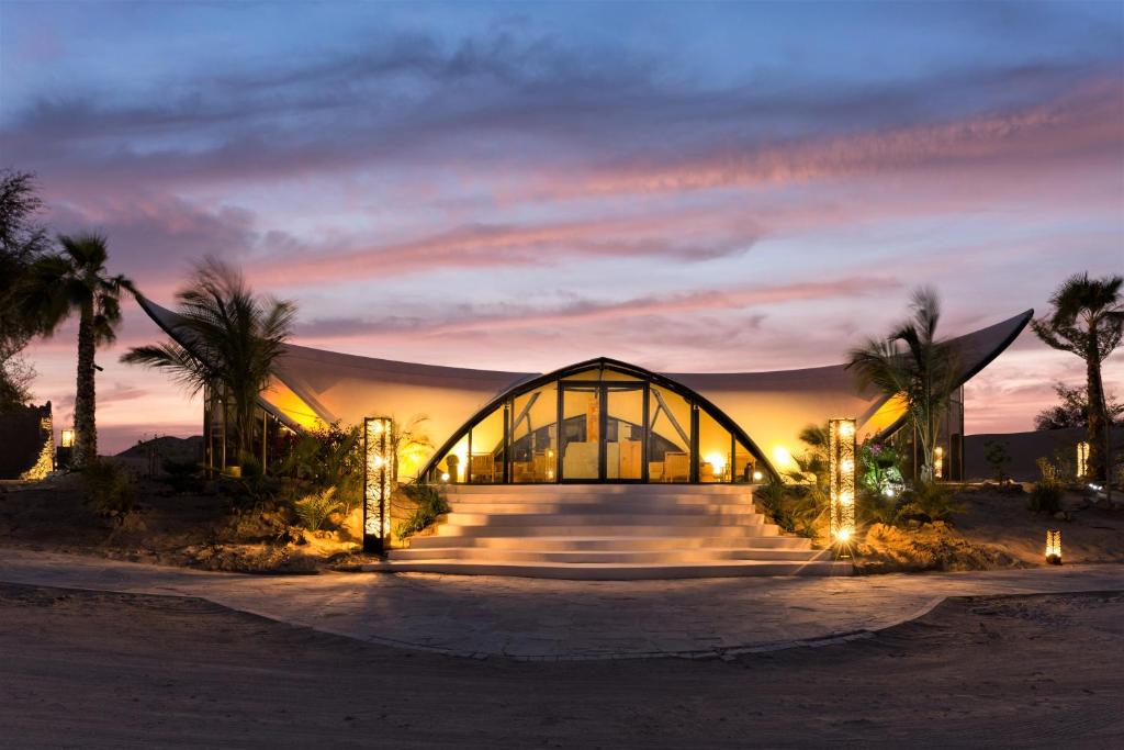 ein Gebäude in der Wüste mit Palmen und Lichtern in der Unterkunft Terra Solis Dubai in Dubai