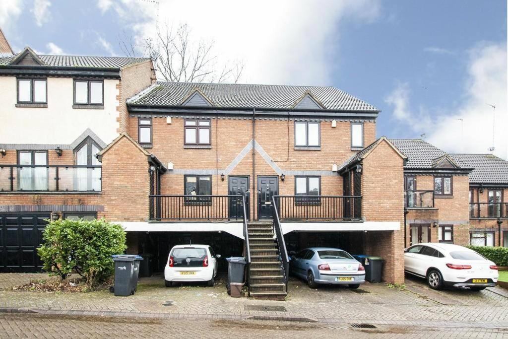 a brick house with cars parked in a parking lot at Lovely 2 bedroom Flat with Free Parking in New Southgate