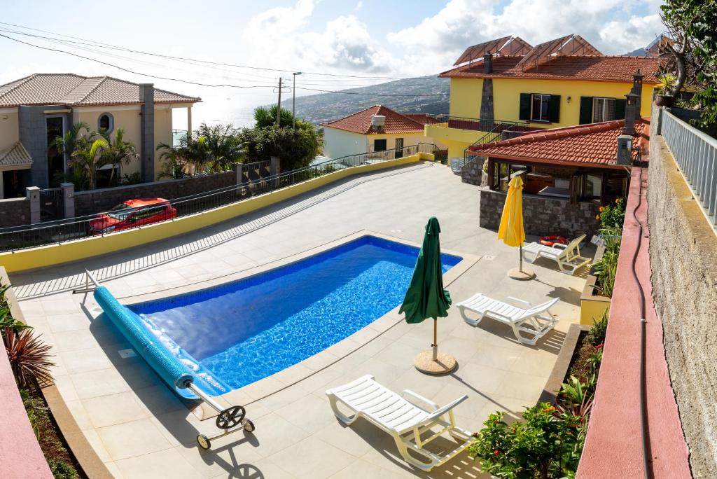 a swimming pool with chairs and umbrellas next to a house at Casa Madeira in Santa Cruz