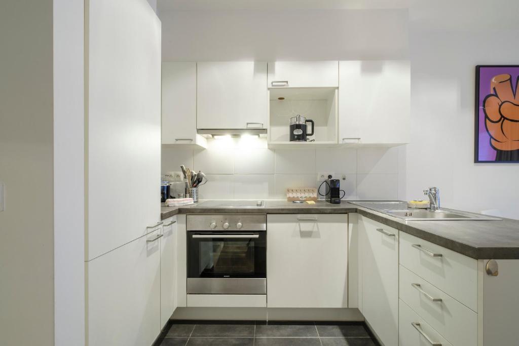eine weiße Küche mit weißen Schränken und einem Waschbecken in der Unterkunft Charmant Studio proche de la Toison d'Or in Brüssel