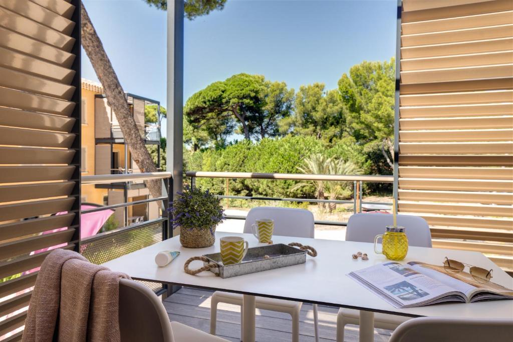 a table on a balcony with a book and chairs at Belambra Clubs Presqu&#39;île De Giens - Riviera Beach Club in Hyères