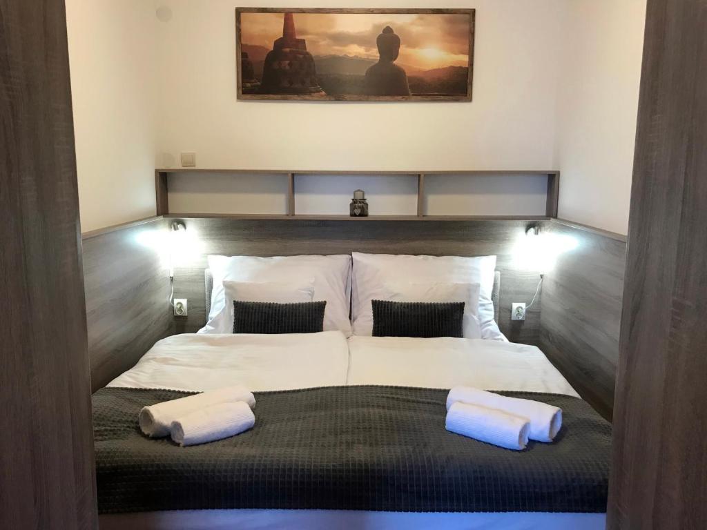 a bedroom with a bed with two pillows on it at Prána Apartman in Herend