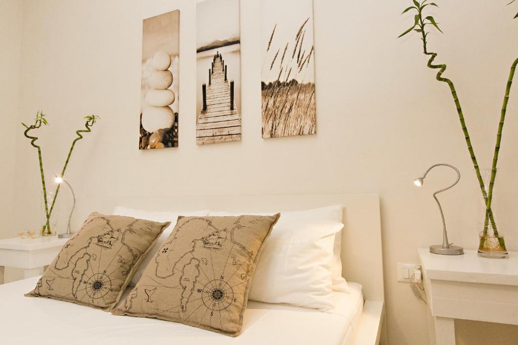 a bedroom with a white bed with three pictures on the wall at B&B Nonno Gino in Marsala