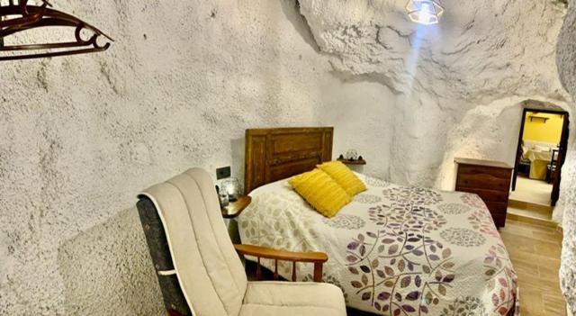 ein Schlafzimmer mit einem Bett und einem Stuhl in der Unterkunft Vivienda Rincon de Mágina in Bedmar