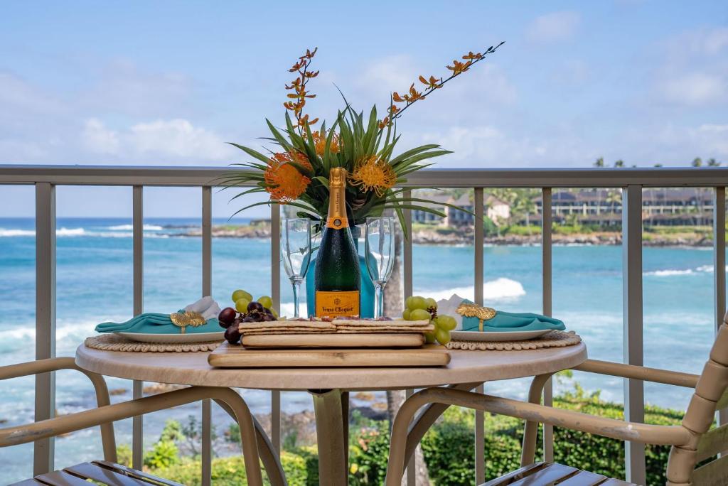 a table with a bottle of wine and a vase of flowers at Napili Shores A203 OF Studio condo in Kahana