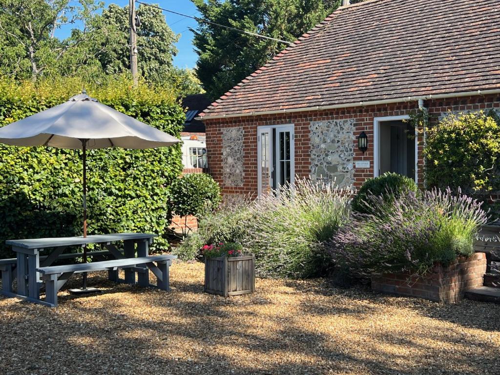 a picnic table and an umbrella in front of a building at Stonehenge Cottages in Salisbury