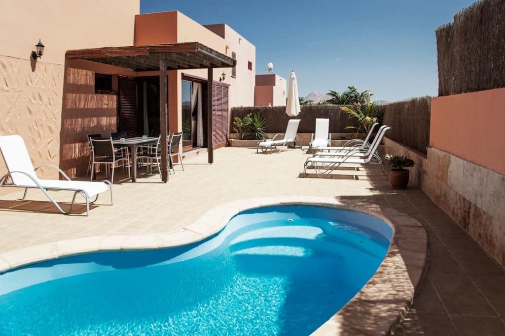 a pool on a patio with chairs and a table at Casa Acebuche in La Oliva
