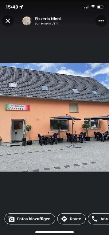 une photo d'un bâtiment avec des tables et des parasols dans l'établissement Klein & Fein Aurachtal, à Neundorf