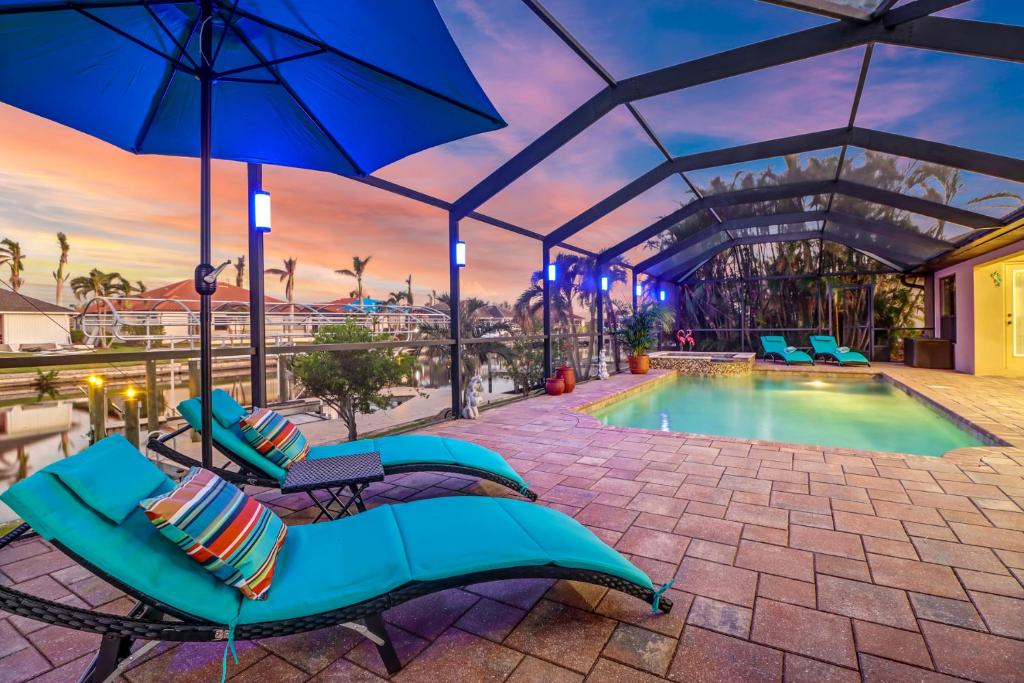 una piscina con sedie a sdraio e ombrellone di Villa Maya Serenity a Cape Coral