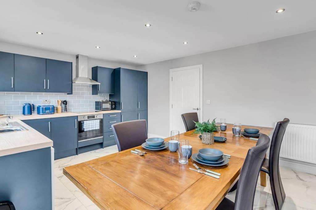 una cucina con tavolo in legno e armadi blu di 8 Beds Denmark House a Norwich