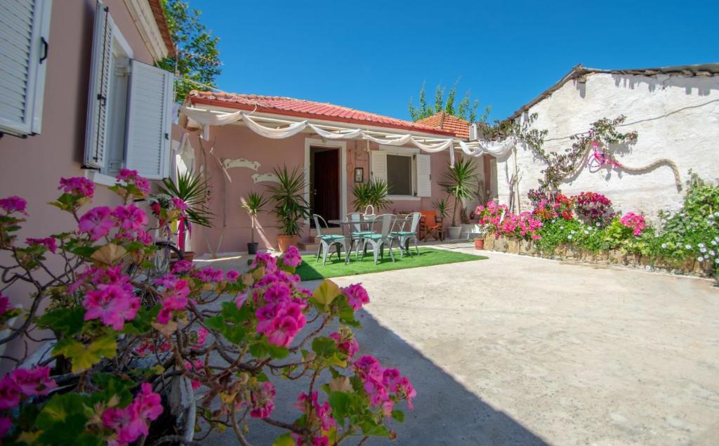 a courtyard of a house with pink flowers at Doras Beach Bungalow B in Plános