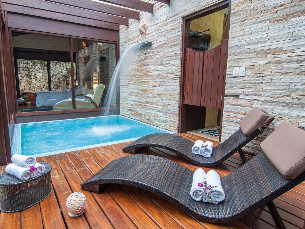 a patio with two chairs and a swimming pool at Pousada Jardim das Montanhas in Monte Verde