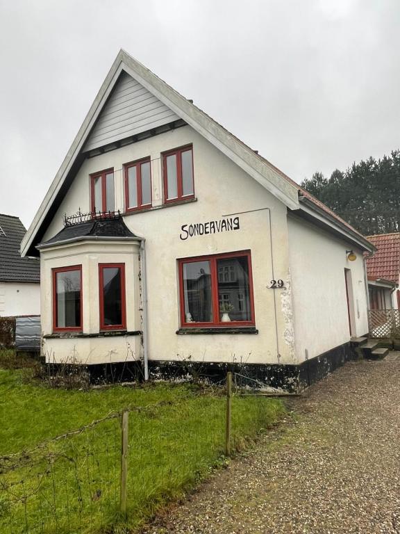 une maison blanche avec des fenêtres rouges dans une cour dans l'établissement Motel Villa Søndervang 3 personers værelse, à Harndrup