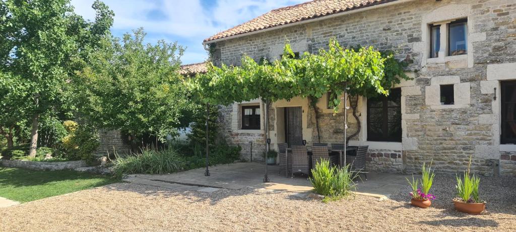 une maison en pierre avec un arbre en face de celle-ci dans l'établissement Gites Chouette, à Bouin