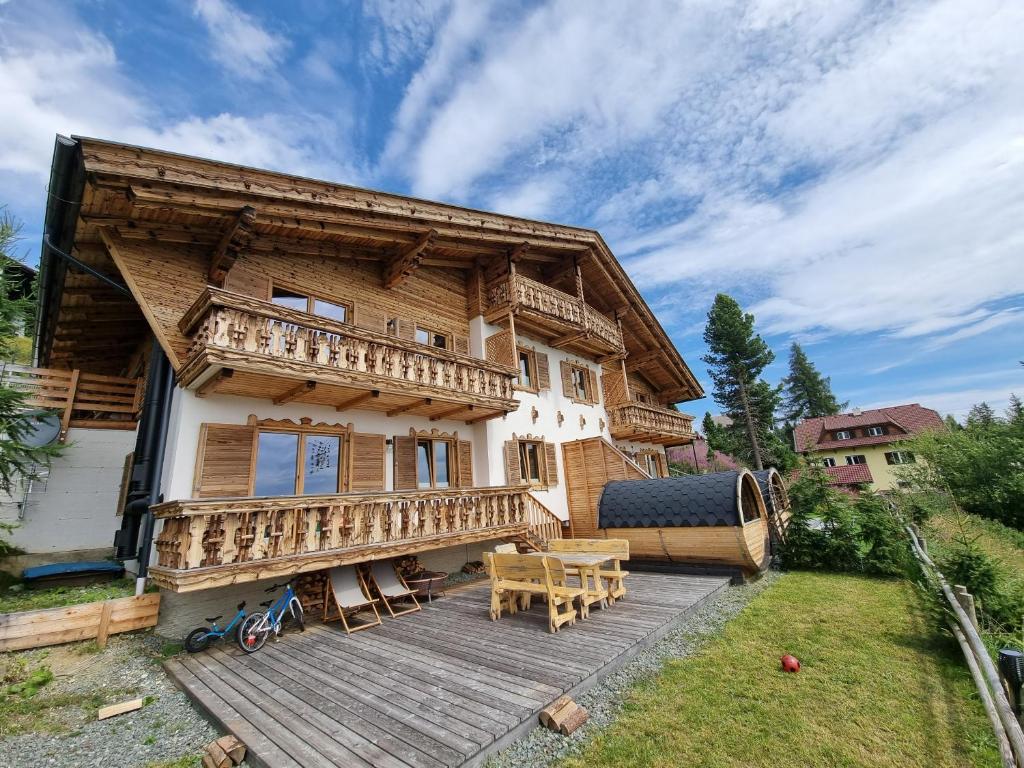 a log house with a deck and a table at Nockalm Appartement Hochrindl 