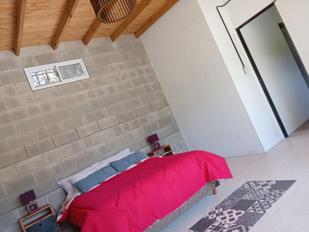 1 dormitorio con cama roja y pared de ladrillo en Casa Quinta Roen Gral Rodriguez zona oeste en General Rodríguez