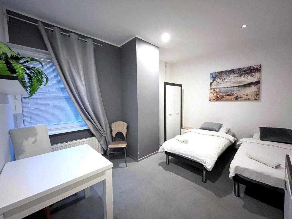 a bedroom with two beds and a table and a window at Keja Aparts - 05 Gdynia Centrum in Gdynia