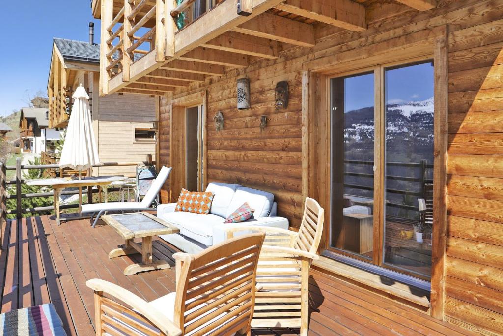 Ce chalet en bois dispose d'une terrasse couverte avec un canapé et des chaises. dans l'établissement Carpe Diem, à Mase